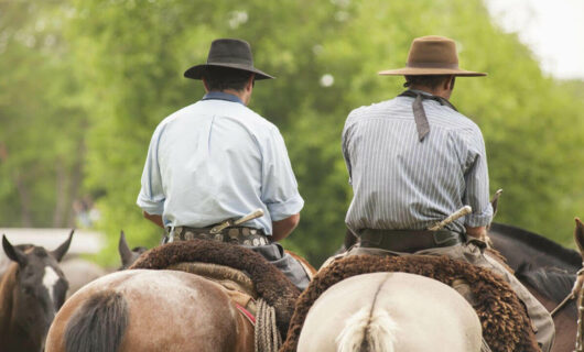 Two gauchos riding horses in the countryside of Argentina