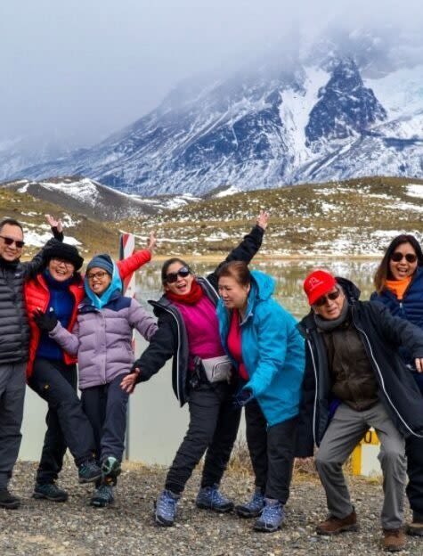 Group of seven people on their vacation in Patagonia with the Andes mountain range in the background.
