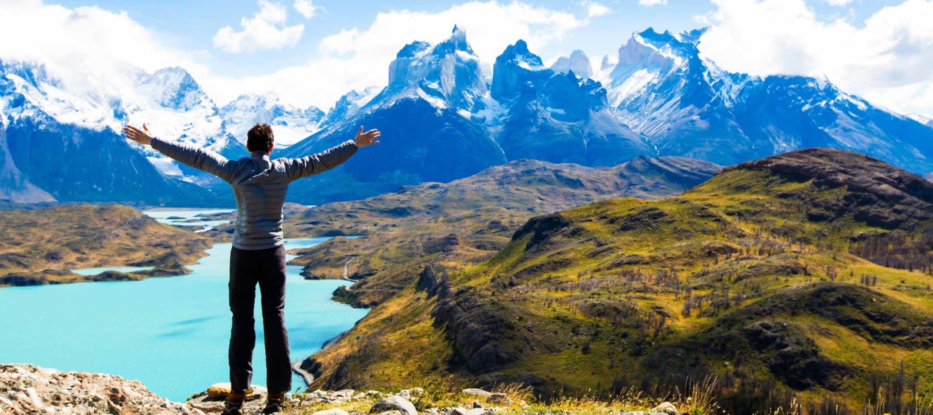 Hiker stands against Torres del Paine on a Chile tour mountains