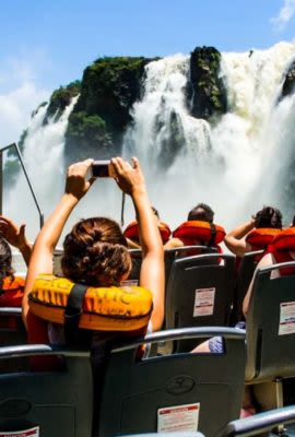 People aboard a boat taking photos of the base of the waterfalls on one of our Iguazu Falls tours