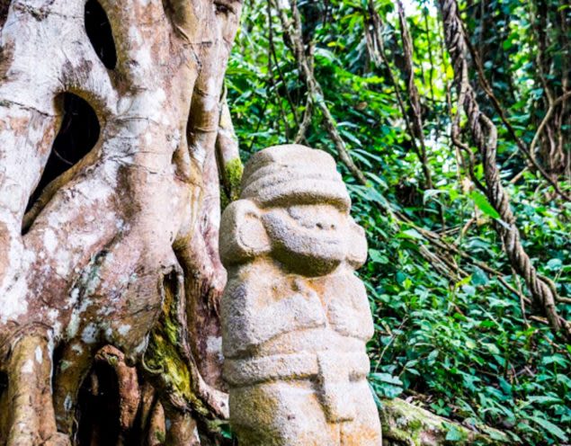 Statue sits in front of jungle tree