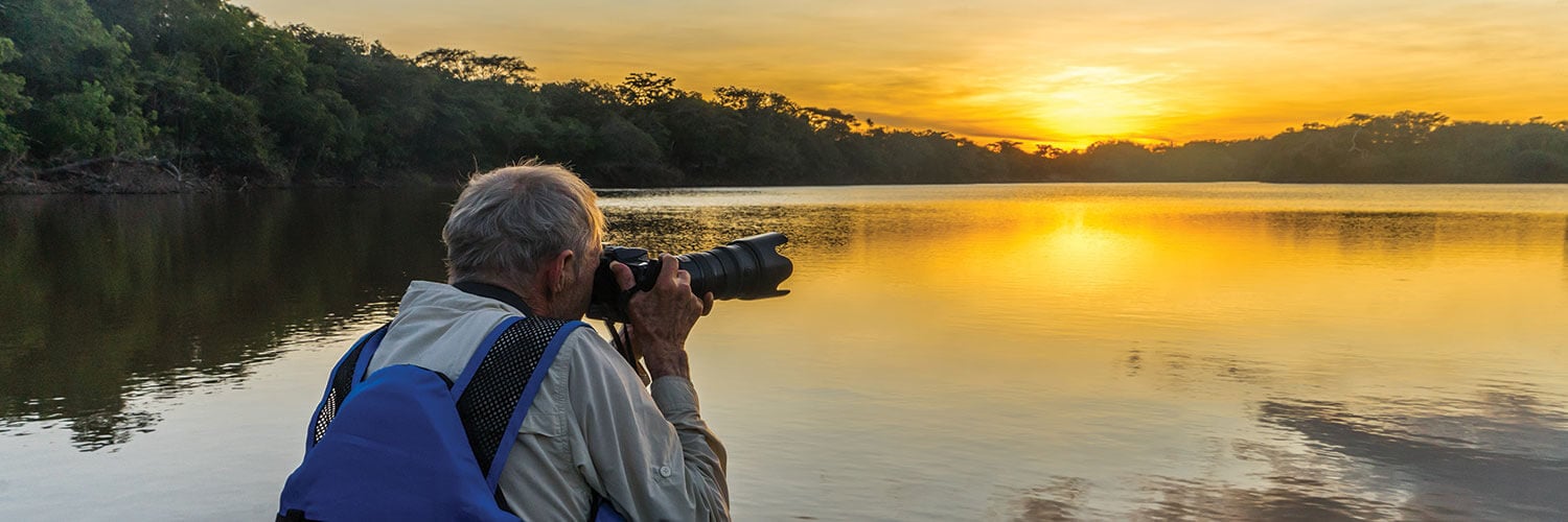 explorer taking a picture of the amazon river at sunset