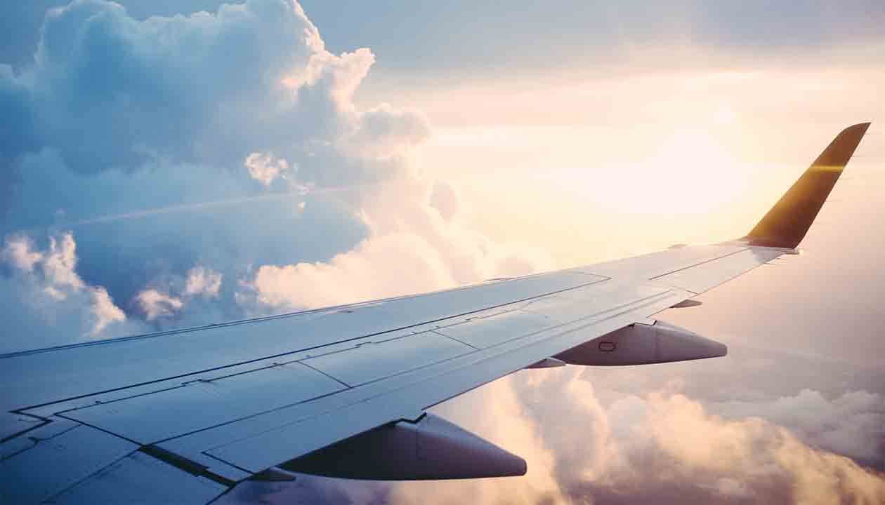 View from an airplane window showing the aircraft’s wing with a dramatic sky filled with clouds and the sun shining brightly—an inspiring sight for anyone dreaming of Patagonia travel and the unforgettable wonders of Patagonia.