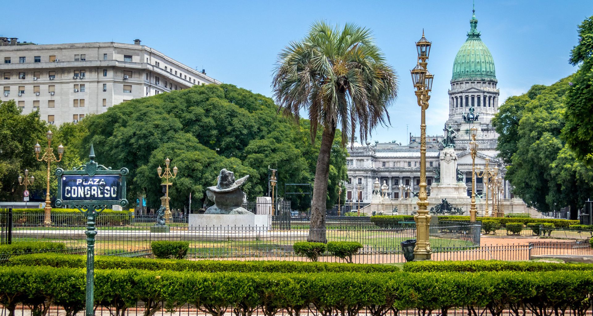 A view of Plaza Congreso in Buenos Aires, Argentina, with its iconic statue, palm trees, manicured lawns, and the National Congress building's green dome—perfect for relaxing before embarking on a Buenos Aires to Tierra del Fuego cruise adventure.