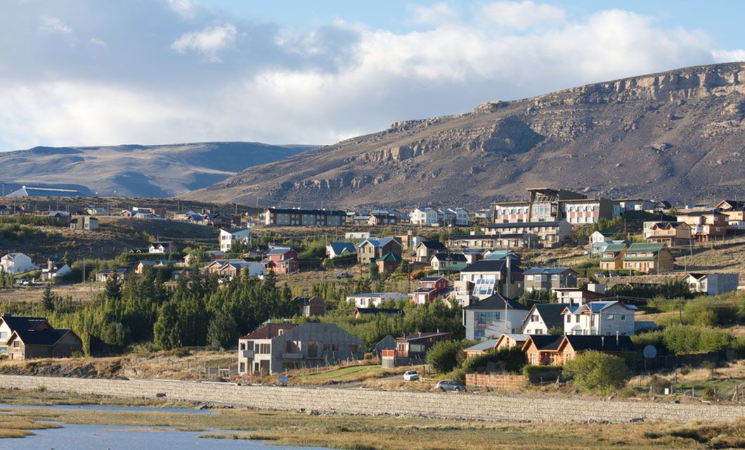 Colorful houses dot a hillside in this small Patagonian town, with rocky mountains behind and a river flowing below—an inviting stop along the Carretera Austral for any Patagonia tour.