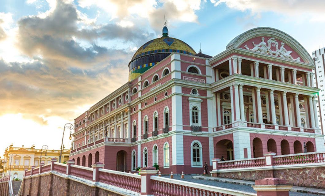 Historic pink and white neoclassical building with ornate details and a blue and gold dome, captured at sunset—a stunning landmark often admired during a Brazil Amazon River Cruise.