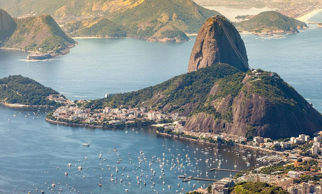 Aerial view of Sugarloaf Mountain in Rio de Janeiro, Brazil, surrounded by water, boats, and lush green hills—inviting you to explore other wonders like the Pantanal and Chapada dos Guimaraes beyond the bustling city shoreline.