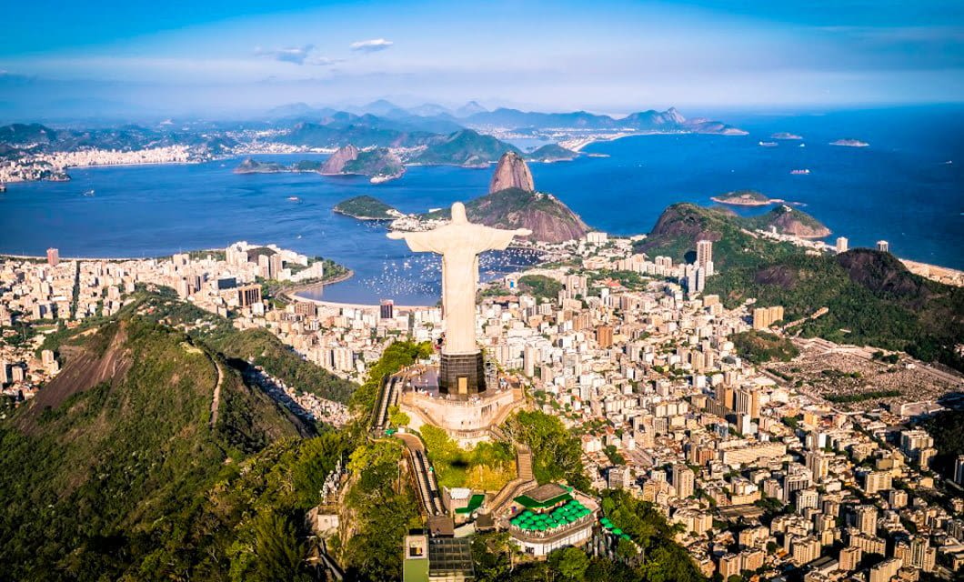 Aerial view of Rio de Janeiro, Brazil, featuring the iconic Christ the Redeemer statue on a mountain, with the cityscape and Sugarloaf Mountain in the background—an unforgettable highlight of any deluxe South America tour.