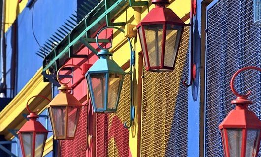 Colorful old-fashioned lanterns hanging on a bright building in Brazil, with walls painted in blue, yellow, and red, create a vibrant street scene—perfect for capturing the lively spirit of a Total Solar Eclipse Tour.