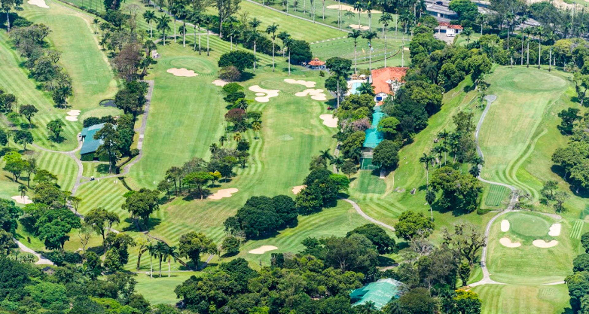 Aerial view of a large, lush golf course with green fairways, sand bunkers, trees, and various buildings surrounded by dense vegetation—one of the region’s premier golf courses near the natural wonders of Iguazu Falls.