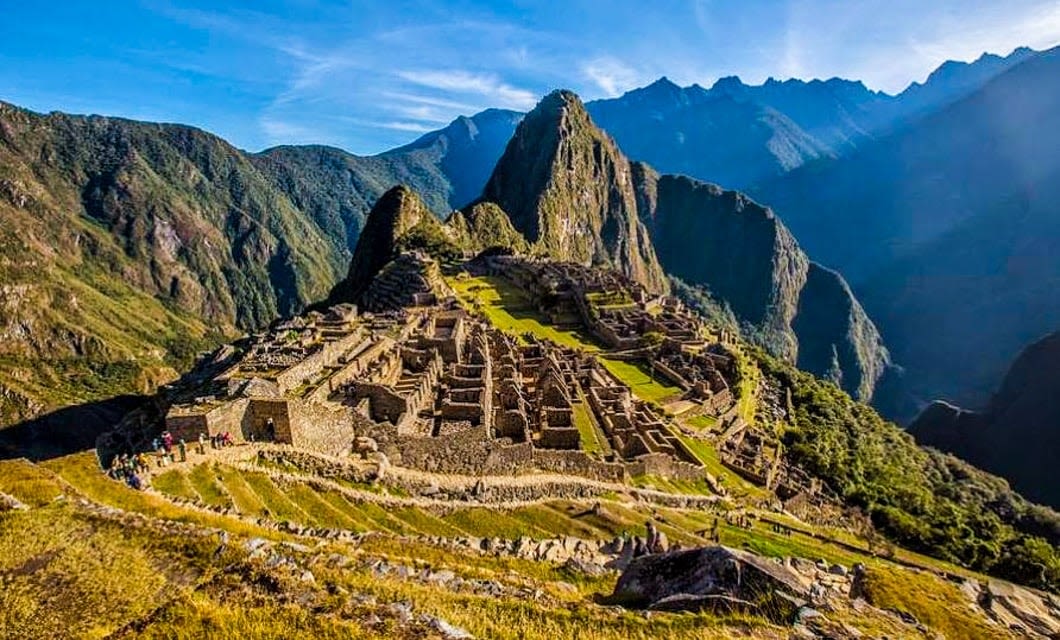 Ancient stone ruins of Machu Picchu sit high on a lush mountain ridge, often included in a Machu Picchu Tour that reveals breathtaking views of steep green peaks and deep valleys in the Peruvian Andes.