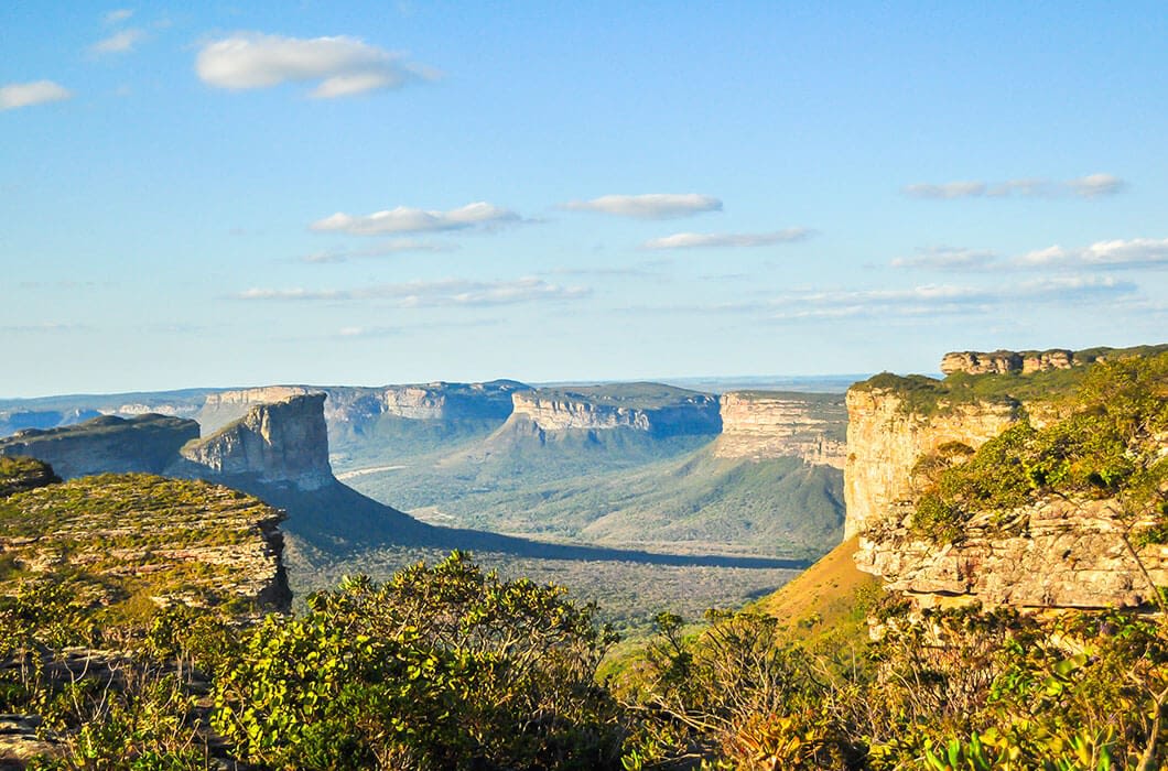 A scenic landscape shows flat-topped cliffs and plateaus covered with greenery under a clear blue sky—one of the stunning Brazil attractions you can experience while exploring Brazil travel destinations.