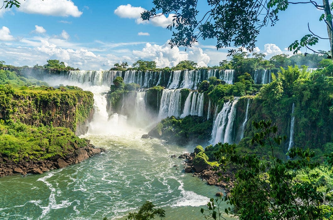 Multiple tall waterfalls cascade over lush, green cliffs into a wide, misty river below—a breathtaking example of Brazil attractions and an absolute highlight for anyone planning Brazil travel.