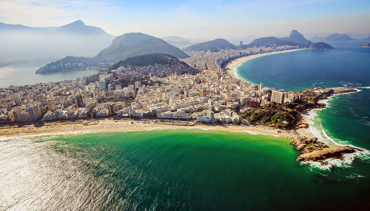Aerial view of Rio de Janeiro, Brazil, showcasing the city’s coastline with sandy shores, turquoise water, and lush mountains under a clear sky—one of the best beaches in Brazil.