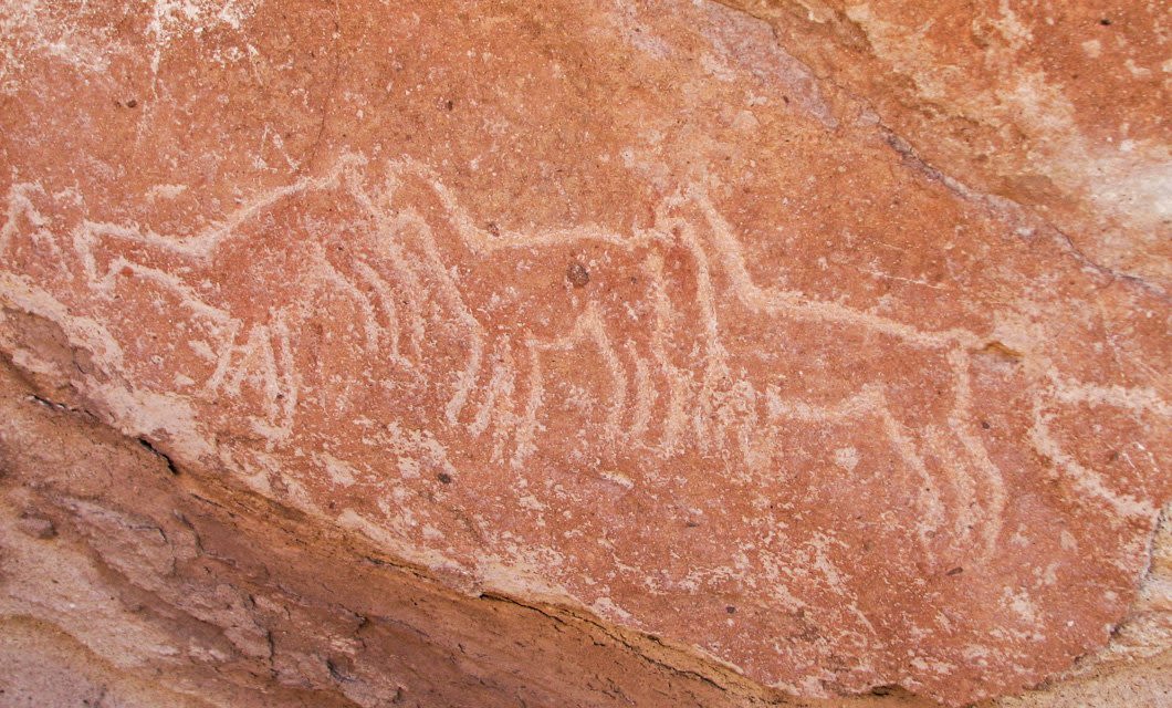 Ancient petroglyphs of three animals, possibly deer or goats, are etched into a reddish-brown rock surface near Tierra Atacama Hotel & Spa. The simple carvings appear weathered by time, capturing the region’s rich history.
