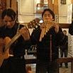 Two musicians perform indoors; one plays a guitar while the other plays panpipes, evoking the spirit of a magnificent trip to Peru. Both wear dark clothing and focus on their instruments.