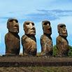 Four large stone moai statues stand in a row on Easter Island, set against a blue sky with scattered clouds and some greenery at their bases—capturing one of the island’s most memorable moments.