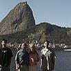 Four people stand in front of water, with Sugarloaf Mountain in Rio de Janeiro visible in the background under a clear sky, capturing a memorable travel experience.