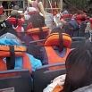 People wearing orange life jackets are seated closely together, facing forward on an outdoor boat trip. The setting appears to be crowded, safety precautions are being observed, and everyone looks ready for a terrific time.
