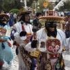 People in colorful, traditional costumes and masks participate in a festive outdoor parade in Peru. They wear elaborate hats, decorated clothing, and carry various accessories, creating lasting memories on this memorable journey down a cobblestone street.