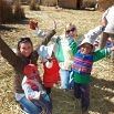 A group of smiling children and an adult with arms raised in excitement are playing outside on a sunny day in a grassy area, capturing the joy of an amazing trip and creating lasting travel experiences together.