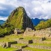 Ancient stone ruins of Machu Picchu with terraces in the foreground and a steep, green mountain rising behind under a partly cloudy sky—one of South America’s top travel recommendations.