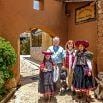 A family of four poses outdoors near an arched doorway and stone path, with views of traditional Andean clothing. Bathed in bright sunlight, they capture the spirit of local culture often enjoyed at scenic locations or hotels in the region.