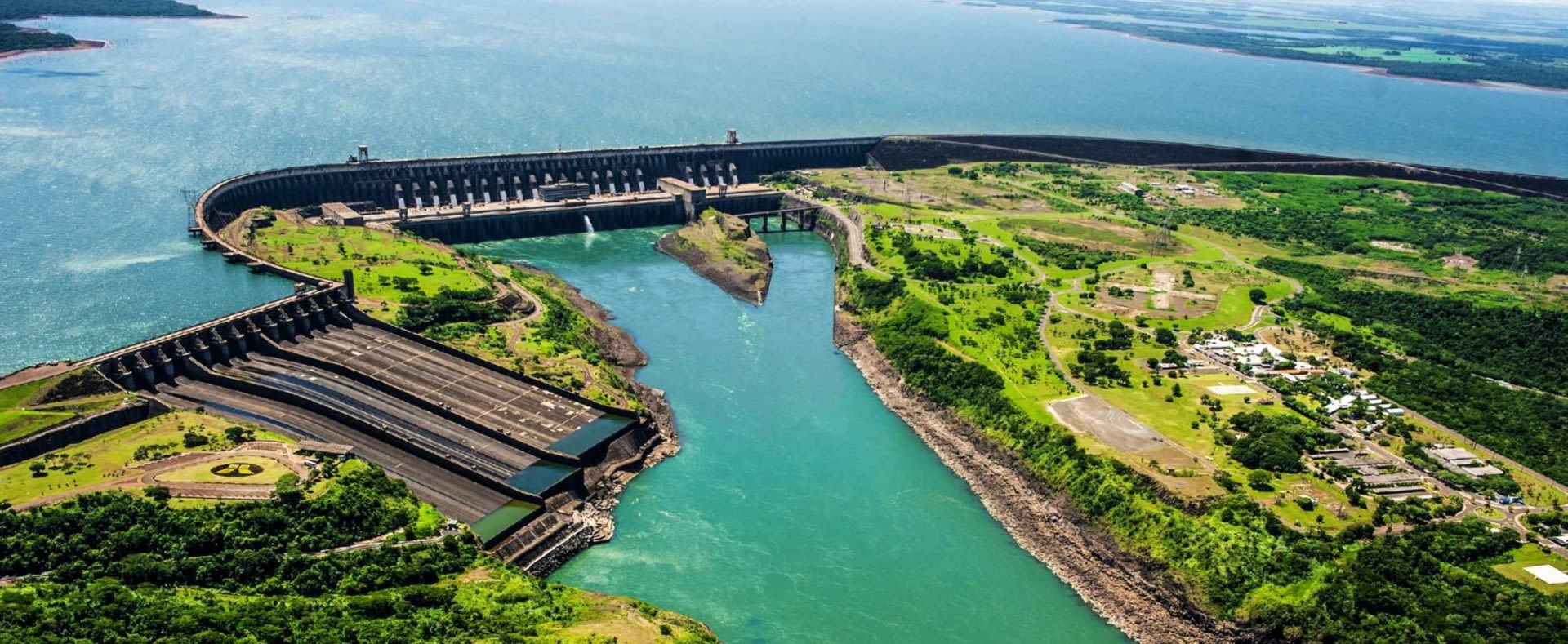 Aerial view of a large hydroelectric dam in Paraguay, surrounded by green landscape and a wide reservoir, with water flowing into a river below—an iconic scene for anyone interested in Paraguay travel or learning about Paraguay visa requirements.