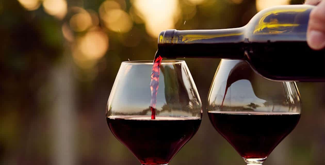 pouring red wine into glasses