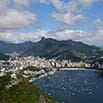 A spectacular aerial view of a coastal city with a bay filled with boats, surrounded by mountains and partly cloudy skies—perfect for travel enthusiasts exploring beyond Iguassu Falls.