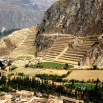 Ancient agricultural terraces built into the side of a steep mountain, with green fields and trees below—a breathtaking view that any travel agent would recommend for those seeking a rugged, mountainous landscape.