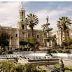A historic plaza with palm trees, a central fountain, and a grand stone cathedral stands under a partly cloudy sky—just the spot that helpful Travel Consultant Clara would recommend for an authentic cultural experience.