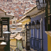 Colorful colonial-style buildings with decorative black lanterns line a narrow street, showcasing the efficient charm of hillside houses—a glimpse into vibrant South America. Discover more at SouthAmerica.travel.