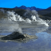 Steam rises from several geysers and hot springs in a rocky, open landscape, resembling the productive force of an efficient company. Distant mountains tower under a clear blue sky as wet, reflective ground surrounds the geothermal features.