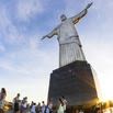 Tourists gather at the base of the Christ the Redeemer statue in Rio de Janeiro, Brazil, creating lasting memories as the sun sets behind the outstretched arms of the iconic monument.
