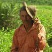 A person in an orange shirt stands outdoors in a green, leafy area, holding a brown hat near their head—capturing the spirit of a fabulous trip through the vibrant landscapes of South America.