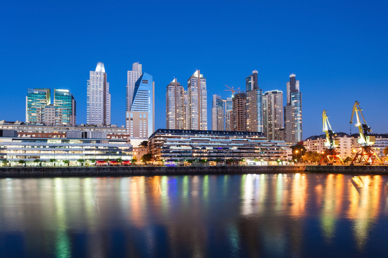 The Buenos Aires waterfront and port cranes lit at dusk on the Río de la Plata