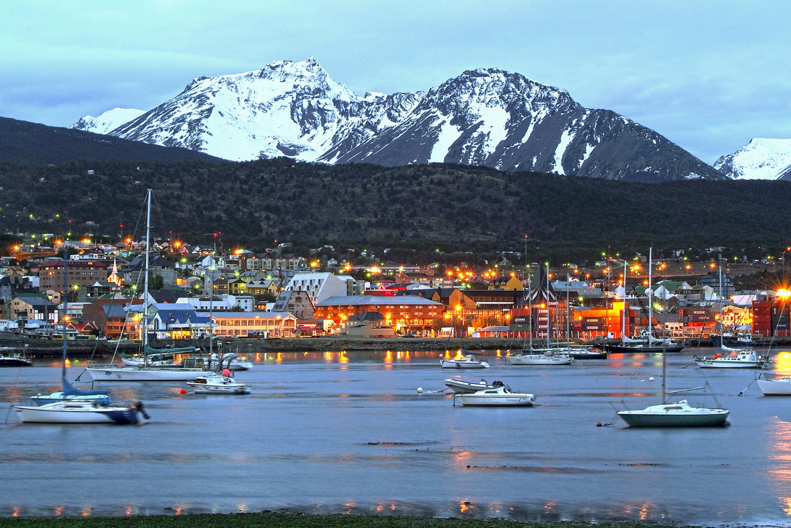 Ushuaia harbour at dusk with moored boats and the snow-covered Martial range behind