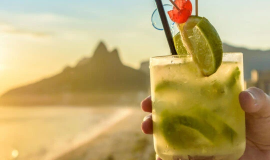 person holding cocktail during sunset on beach