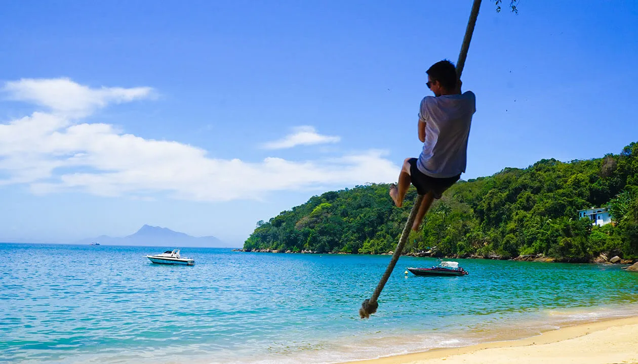 man swinging on rope in ilha grande