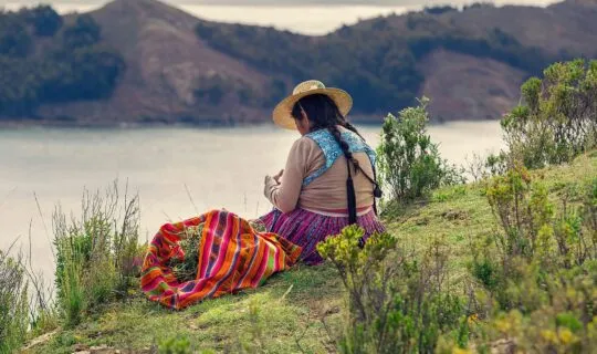 Native woman of Bolivia sitting by lake