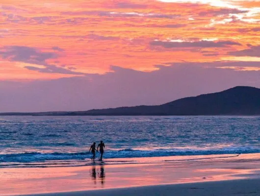 couple walking on beach at sunset