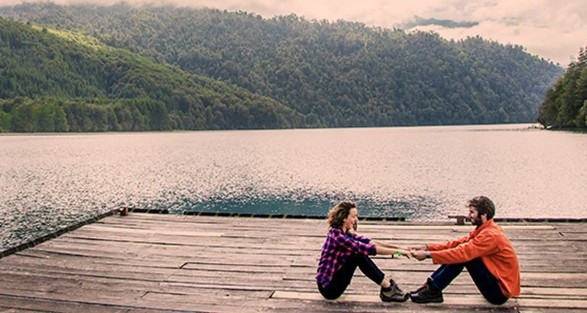 couple-relaxing-and-holding-hands-on-serene-dock-over-lake