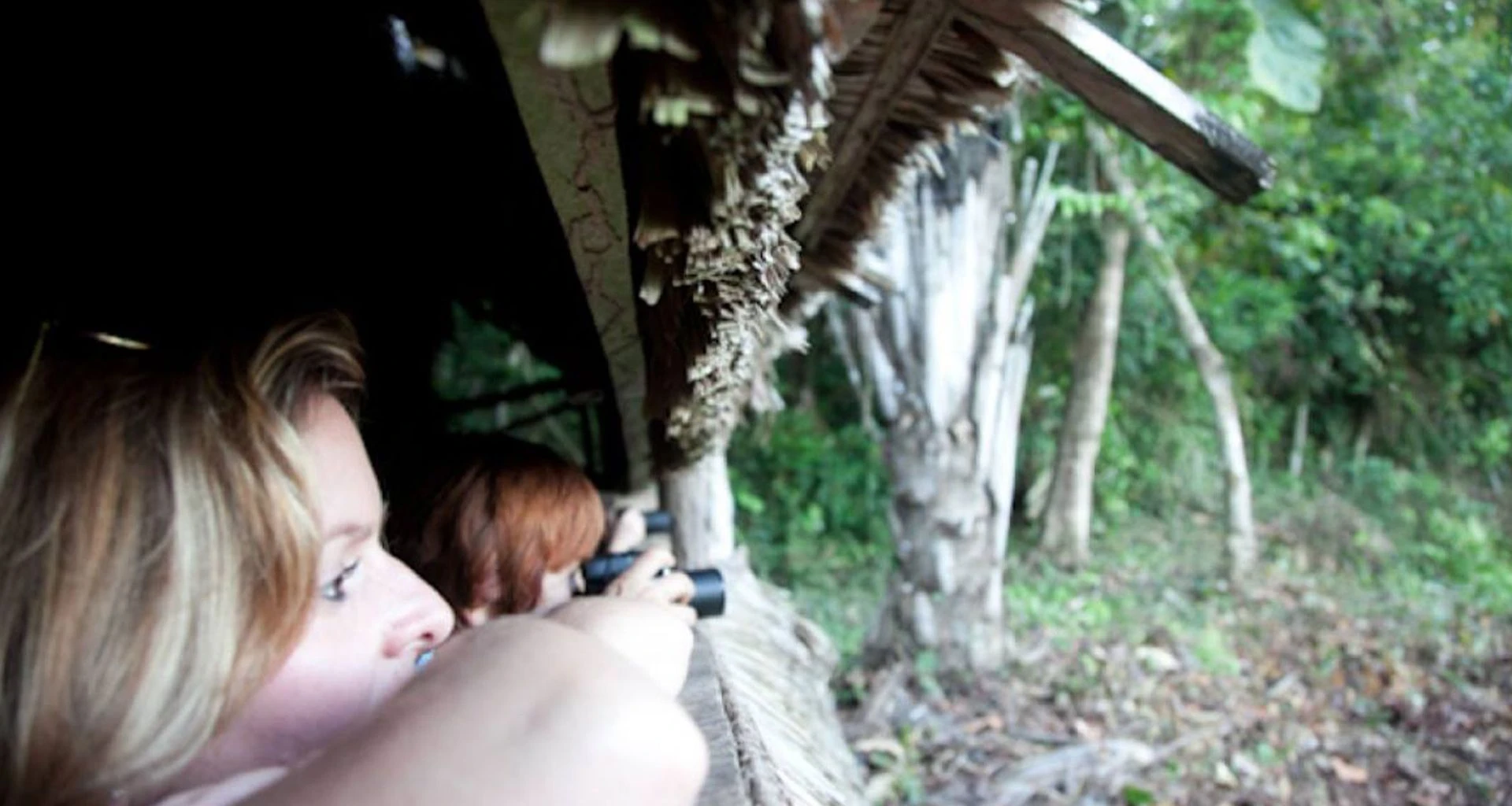 Travelers look through binoculars at Inotawa Lodge
