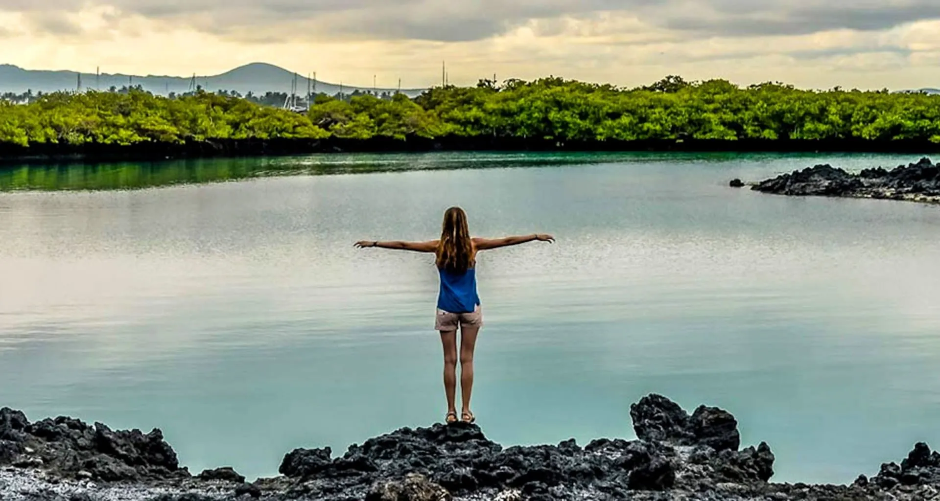 Woman holds arms out in front of lake