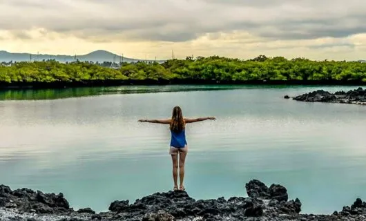 Woman holds arms out in front of lake