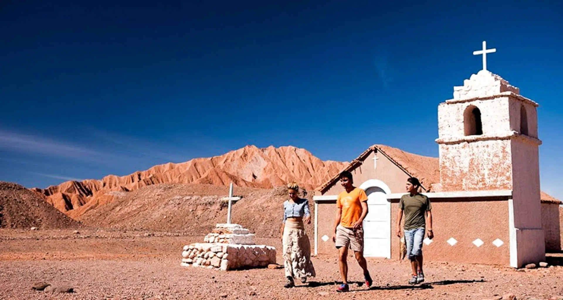 Travelers walk past small building in Atacama Desert