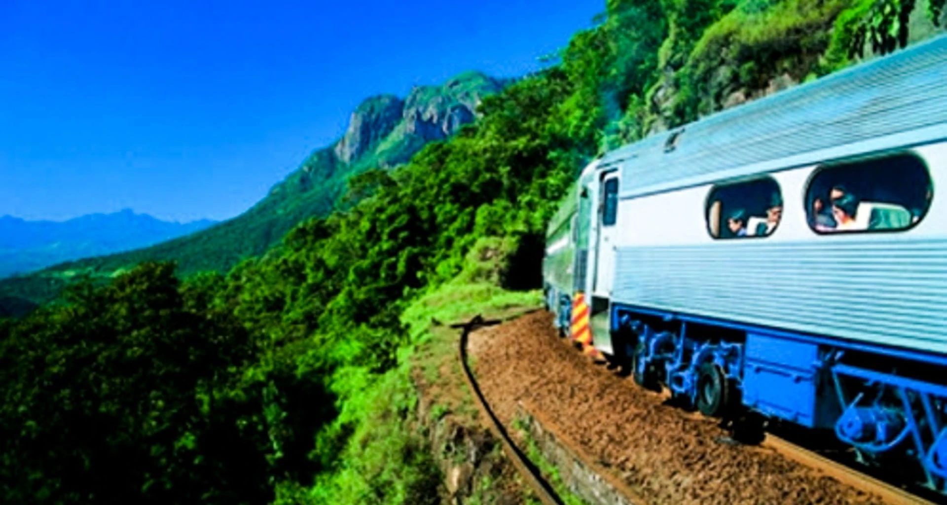 Blue train runs along railway in Brazil forest