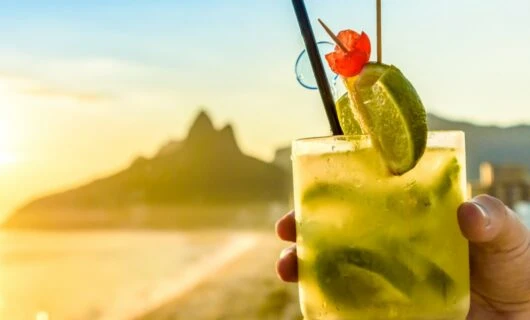 Hand holds cocktail on Brazil beach