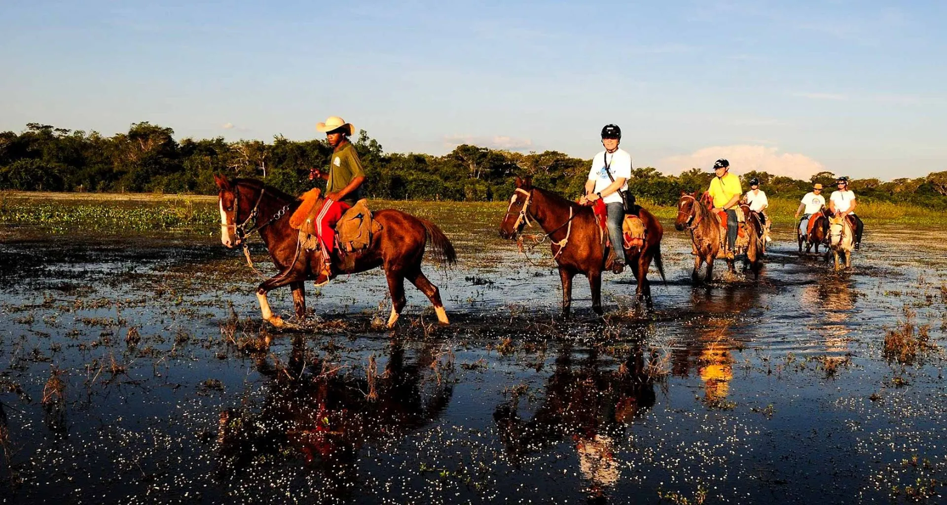 Travelers ride horses through Brazil wetland